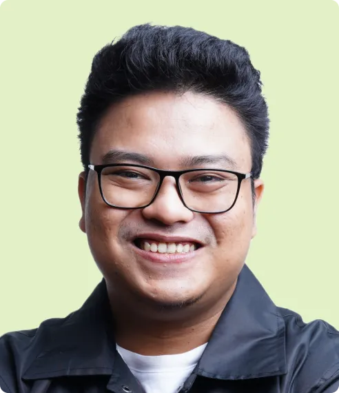 Irfan Kurnia smiling, wearing glasses and a dark shirt